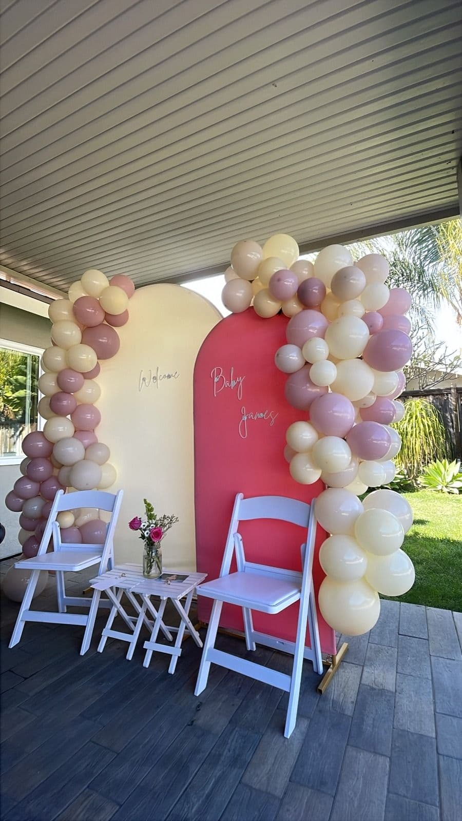 Blush, mauve and cream balloon garland framing a two-panel arched backdrop at an outdoor baby shower