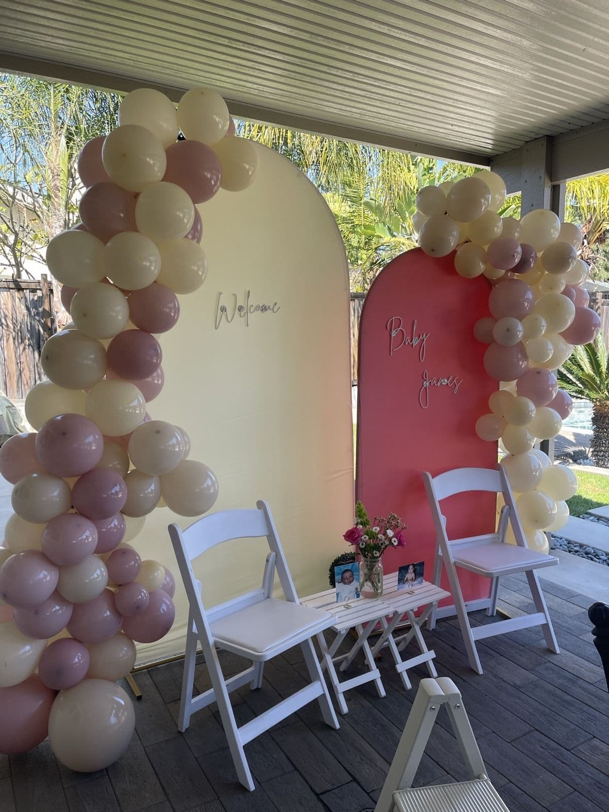 Cream and mauve balloon garland framing two arched backdrop panels on a patio