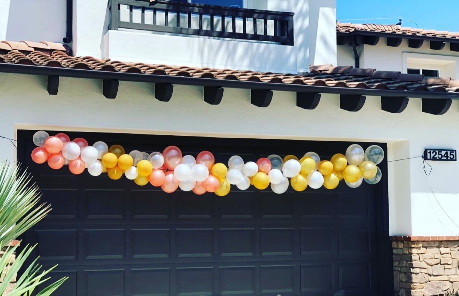 Coral, gold and white balloon garland running across a garage front