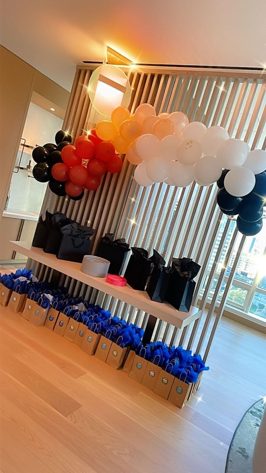 Orange, black and white balloon garland above a shelf of party favors