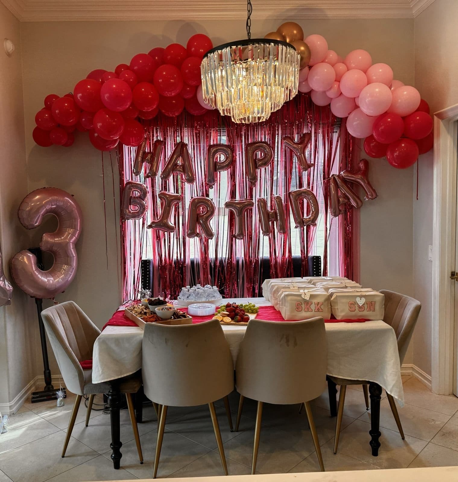 Red and blush balloon garland with a fringe backdrop over a birthday table