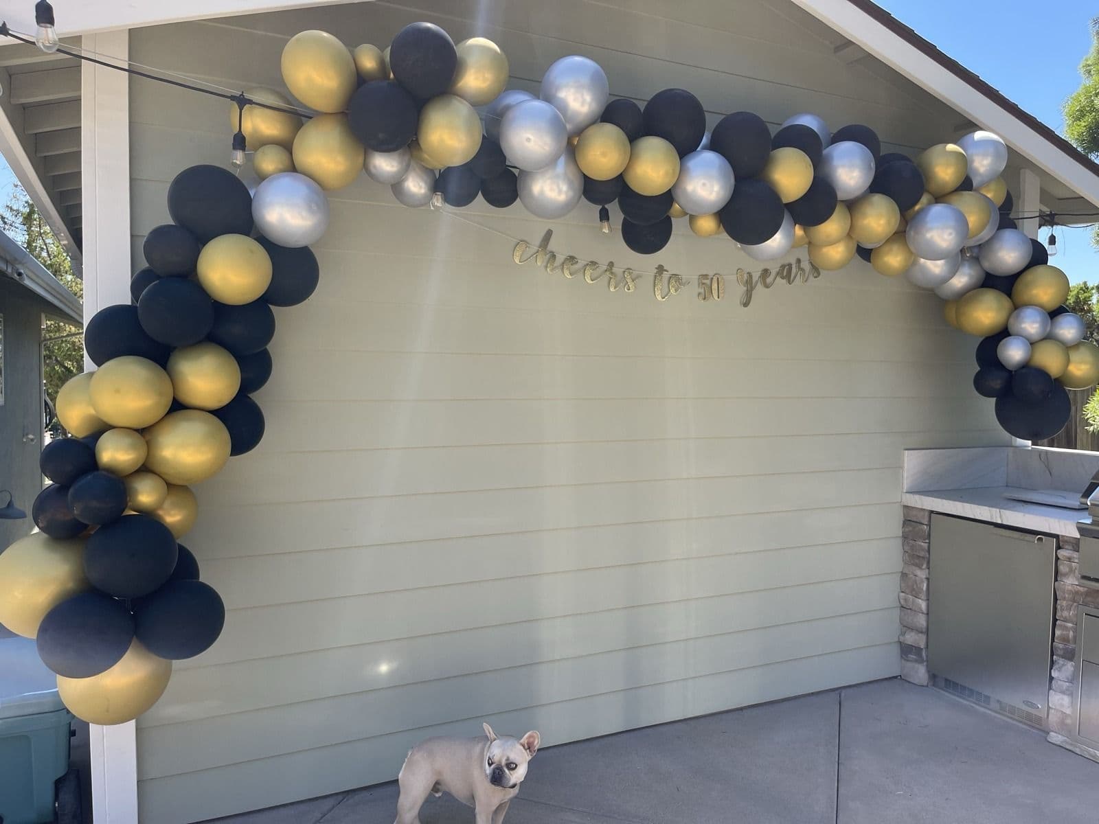 Navy, gold and silver balloon garland arching across the back of a house