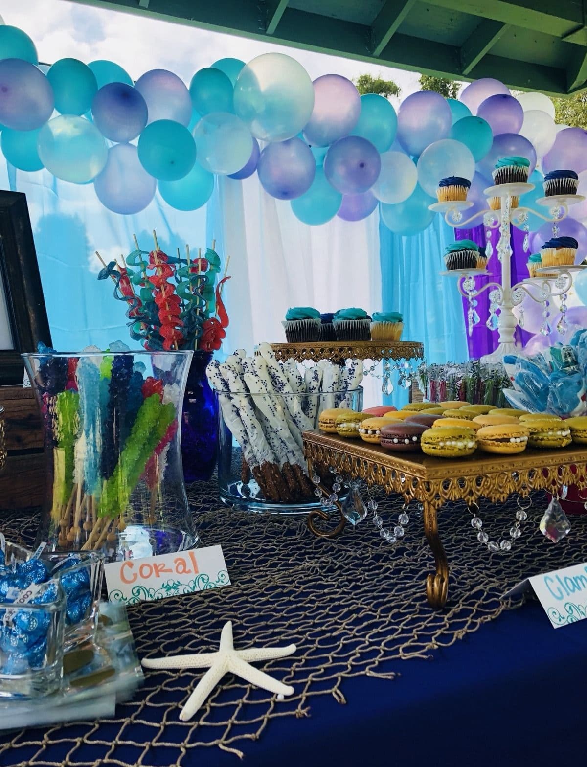 Blue and purple balloon garland above an under-the-sea themed dessert table
